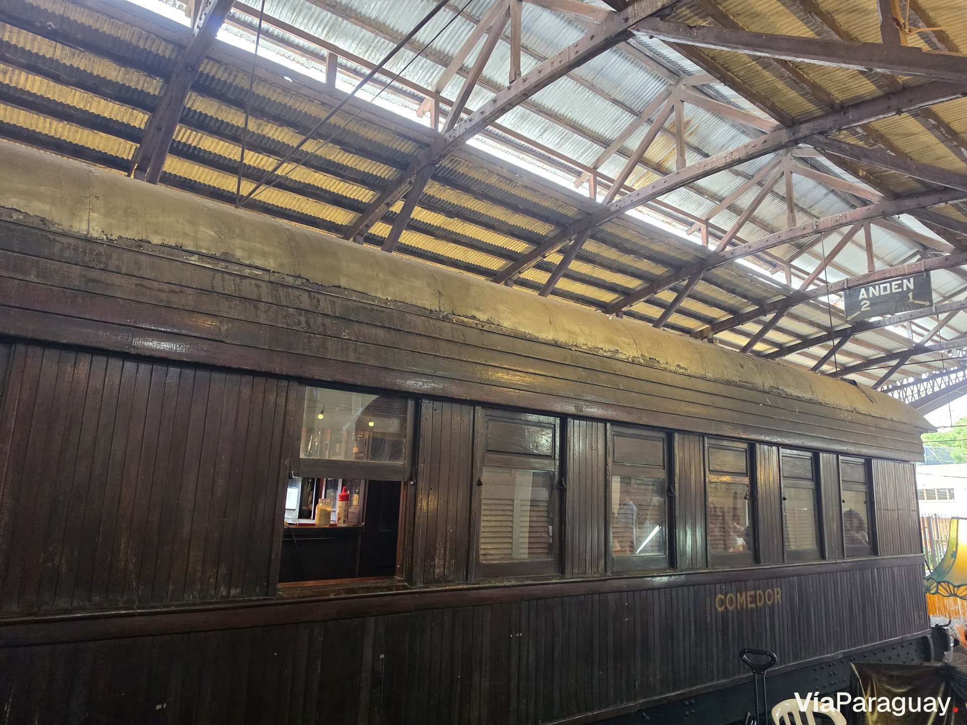 Coche de madera bajo la nave de la estación, con el rótulo «Comedor»